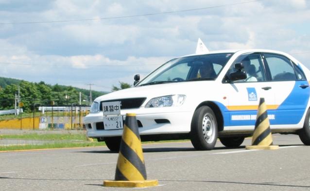 パイロンを使った実技教習を行う白い教習車