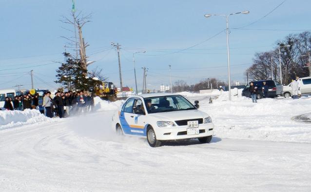 雪道を走行する教習車がカーブでスリップしながら進む様子。